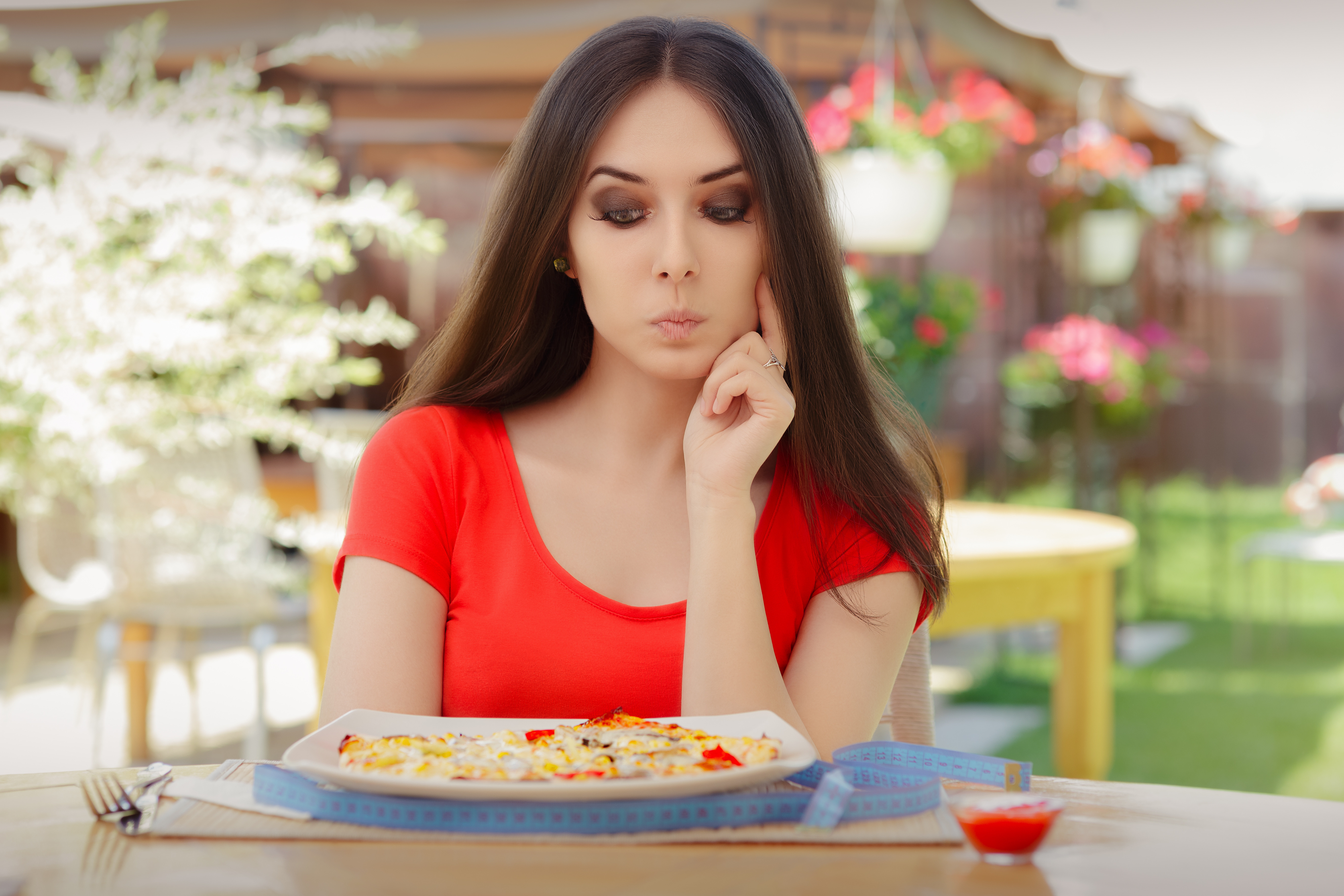 37428015 – young woman thinking about eating pizza on a diet