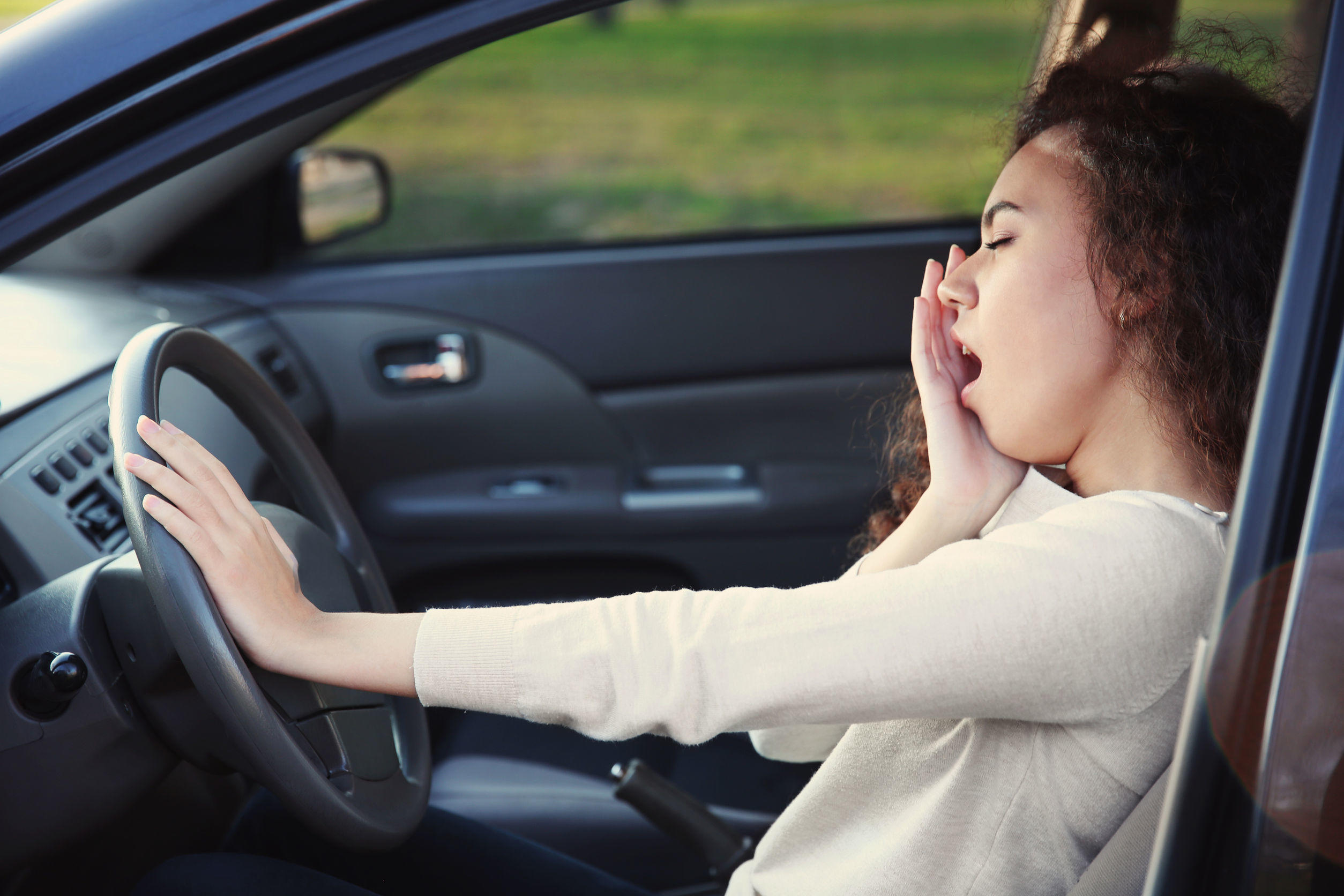 95971900 – a woman feeling sleepy and yawning in the car